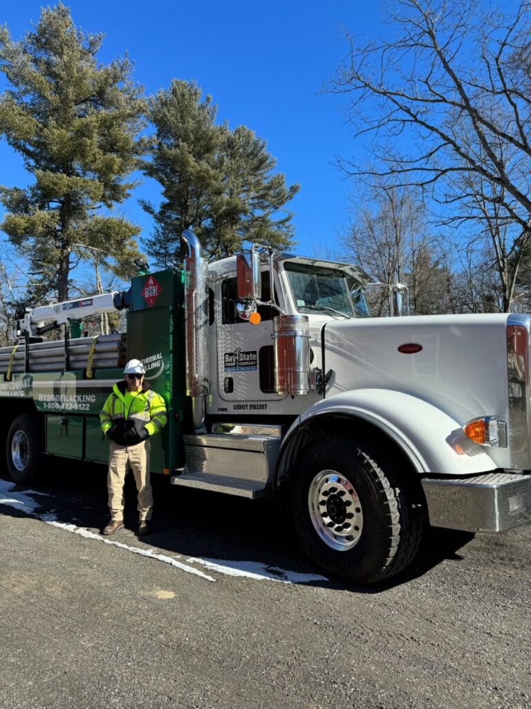 A worker in high-visibility clothing standing in front of a white towing truck.